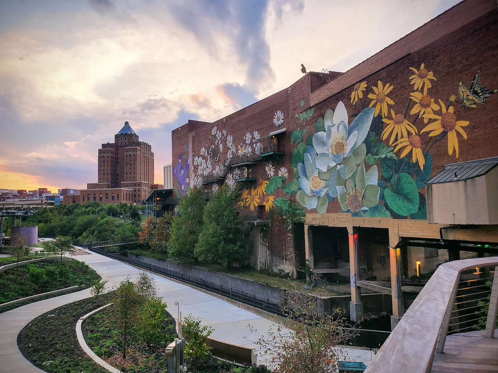 Lock 3 and Canal Square in downtown Akron at dusk, with a
          painted flower mural on the brick wall beside the towpath